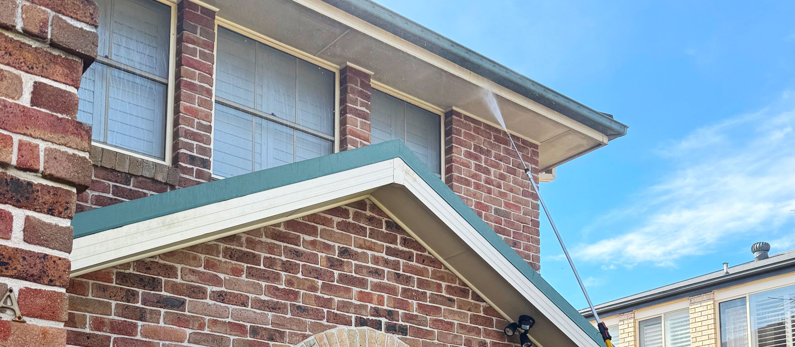 Pressure washing the eaves and gutters of a brick home, Sydney